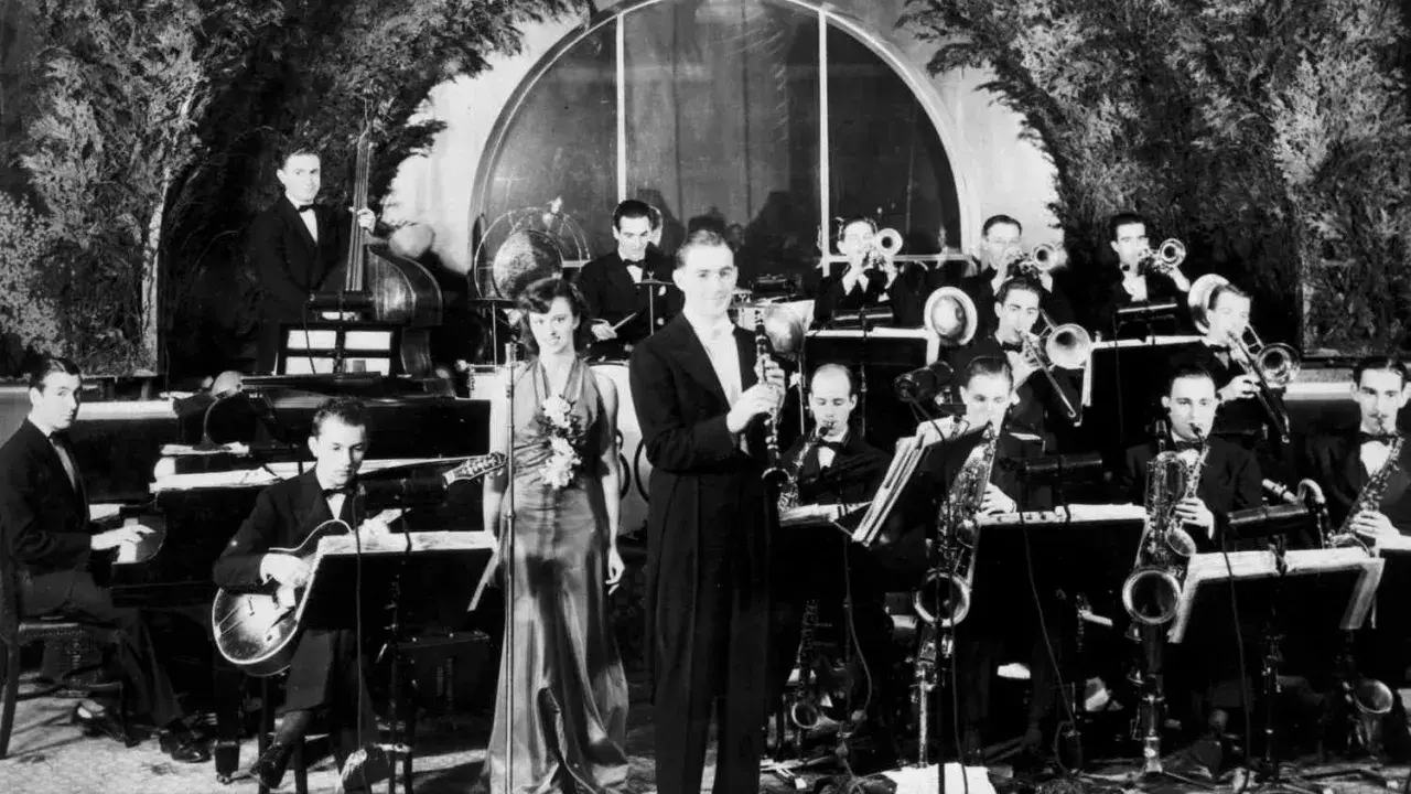 Orkiestra grająca muzykę lat 30. na scenie. Wokalistka w eleganckiej sukni, klarnetysta, gitarzysta i sekcja dęta.