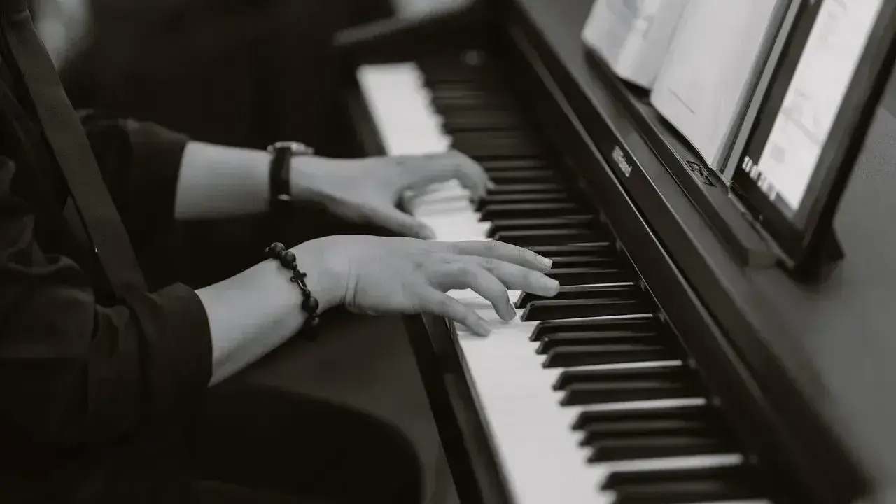 Dłonie grające na pianinie, tworząc improwizowany kierunek w muzyce jazzowej.