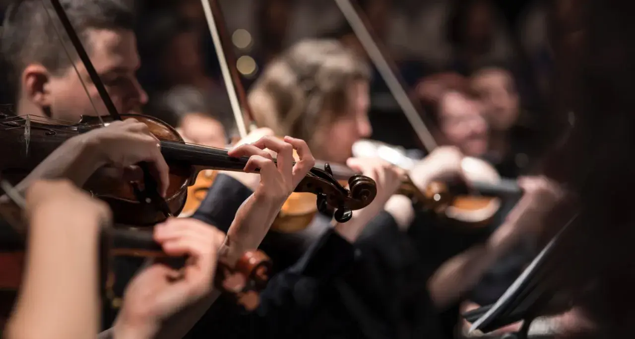 Orkiestra wykonuje muzykę renesansu w Polsce. Skupienie na dłoniach grających na skrzypcach.