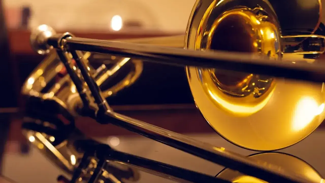 Błyszczące, złote puzony, różne rodzaje instrumentów dętych blaszanych, odbijające się w lustrzanej powierzchni.