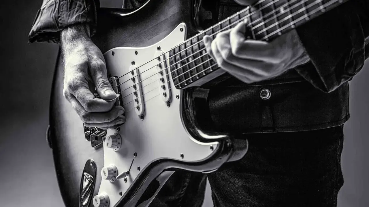Ręce muzyka grające na gitarze do metalu. Czarno-białe ujęcie z bliska.