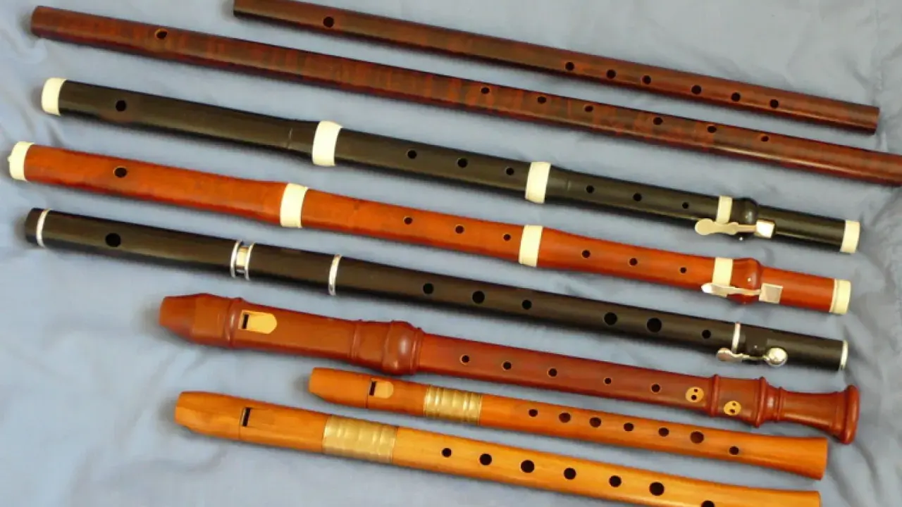Różnorodne instrumenty renesansu, w tym flety proste o różnych rozmiarach i materiałach, ułożone na niebieskim tle.