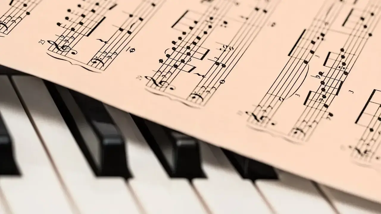 Partytura muzyczna na klawiaturze pianina. Widoczne nuty i klucze, które oddają bogate **cechy muzyki barokowej**.