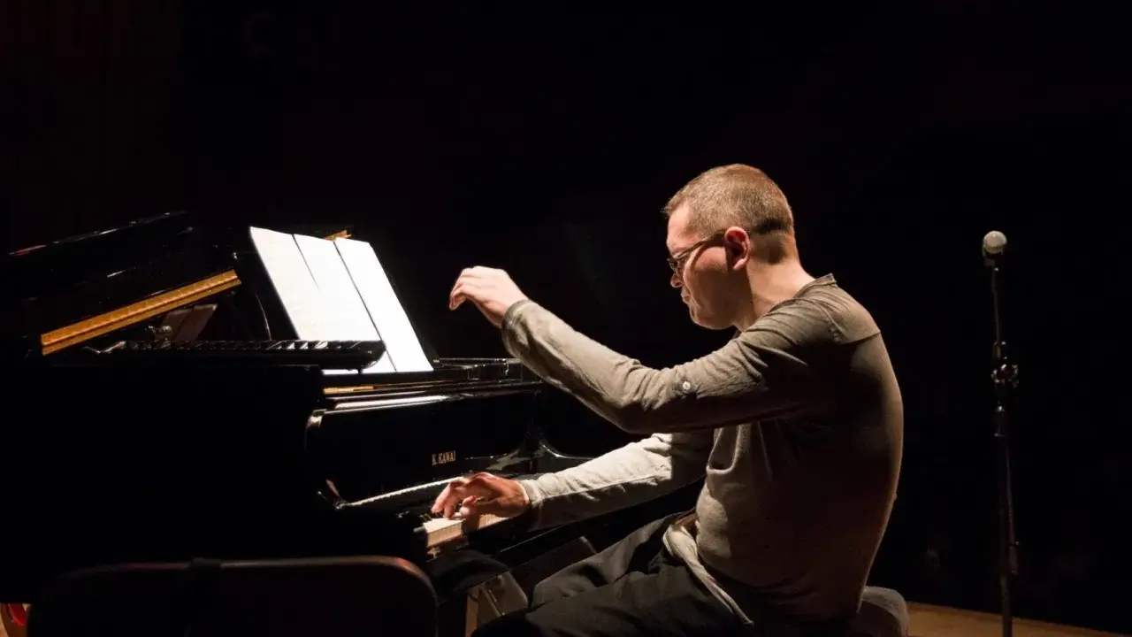 Znany polski kompozytor i pianista jazzowy, w skupieniu gra na fortepianie podczas koncertu.