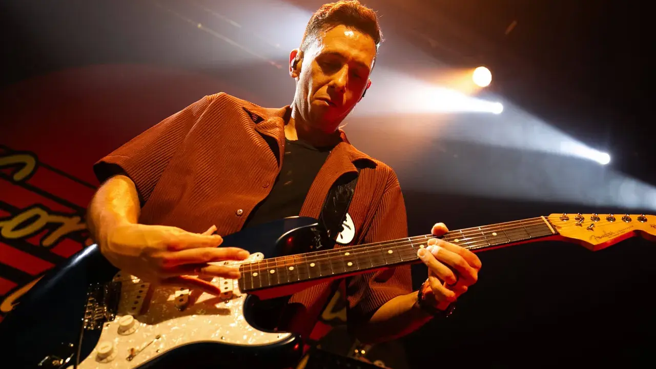 Cory Wong w akcie tworzenia muzyki na scenie, skupiony na grze na gitarze elektrycznej.