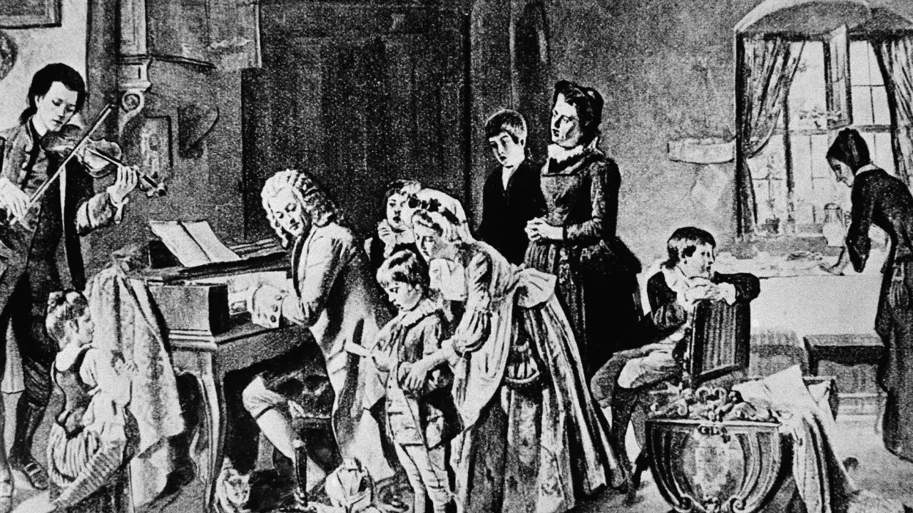 Johann Sebastian Bach z dziećmi w muzycznym domu. Syn gra na skrzypcach, ojciec przy klawikordzie, a reszta rodziny słucha.