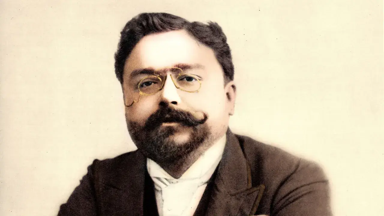 Portret kompozytora Isaaca Albéniza w okularach i z wąsami.