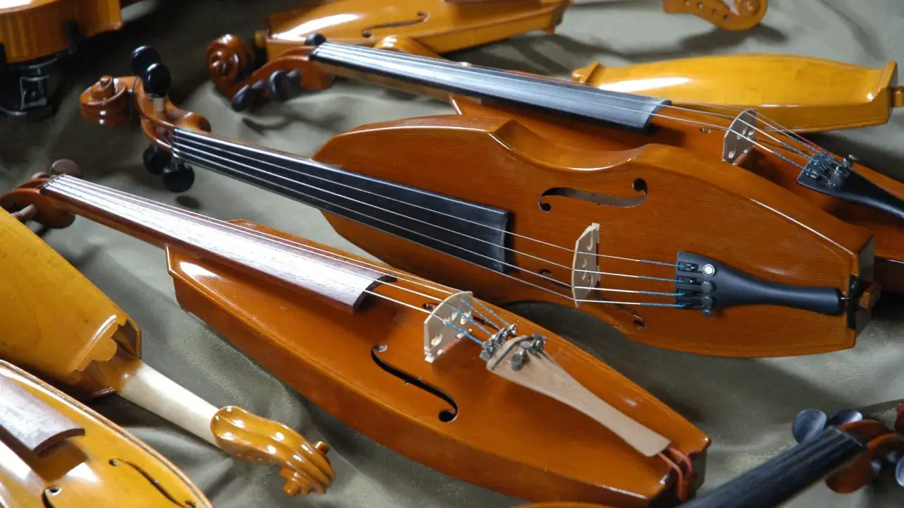 Kolekcja zabytkowych, drewnianych instrumentów smyczkowych. Te średniowieczne instrumenty, z ich ciepłym, lakierowanym wykończeniem, czekają na muzyków.