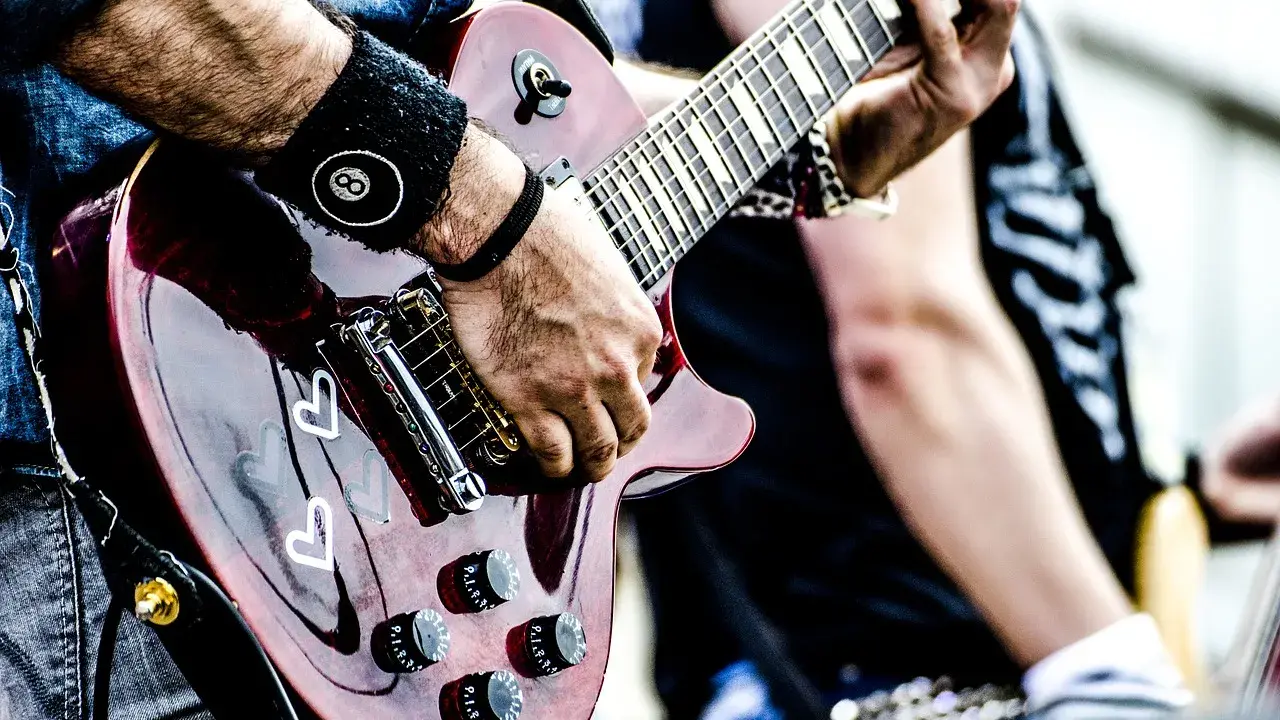 Muzyk gra na gitarze, przygotowując się do wykonania coverów piosenek.