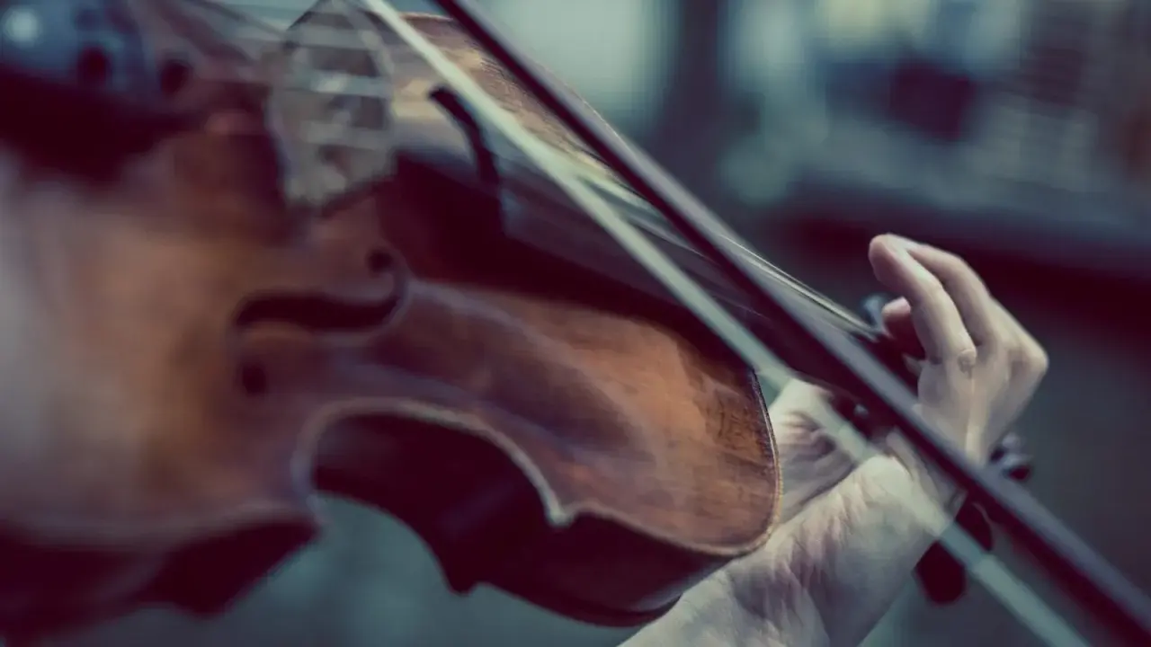 Dłoń gra na skrzypcach Stradivarius, wydobywając z nich magiczne dźwięki.
