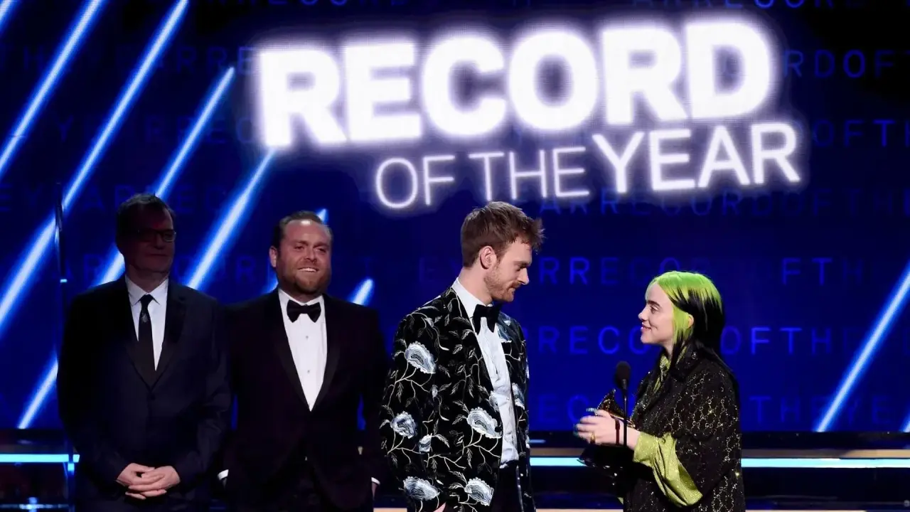 Billie Eilish odbiera nagrodę za nagranie roku. Na scenie towarzyszą jej Finneas O'Connell i inni.