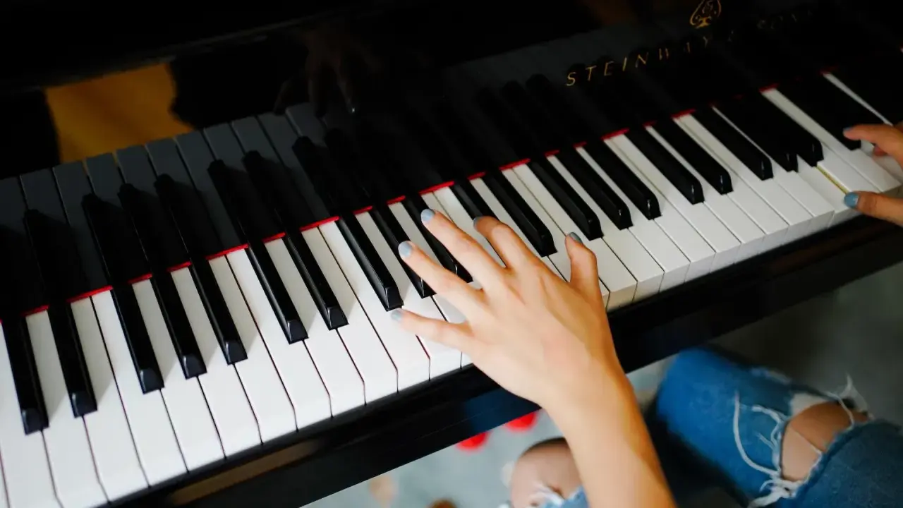 Dłoń grająca piosenkę na fortepianie Steinway.