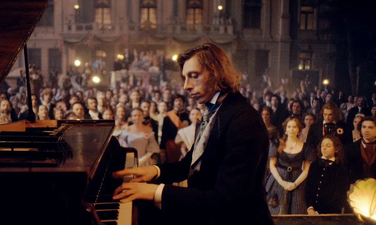 Młody Fryderyk Chopin gra na fortepianie przed zgromadzoną publicznością.