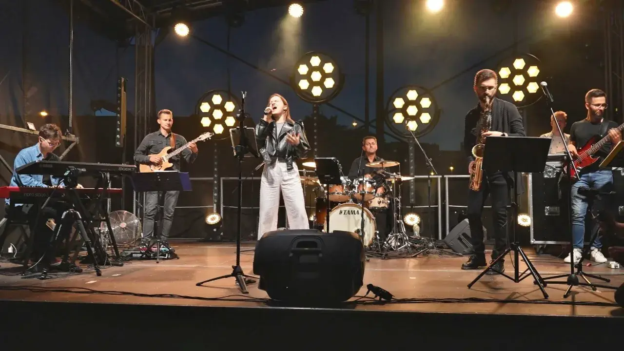 Zespół muzyczny na scenie: wokalistka, gitarzysta, klawiszowiec, saksofonista, basista i perkusista.