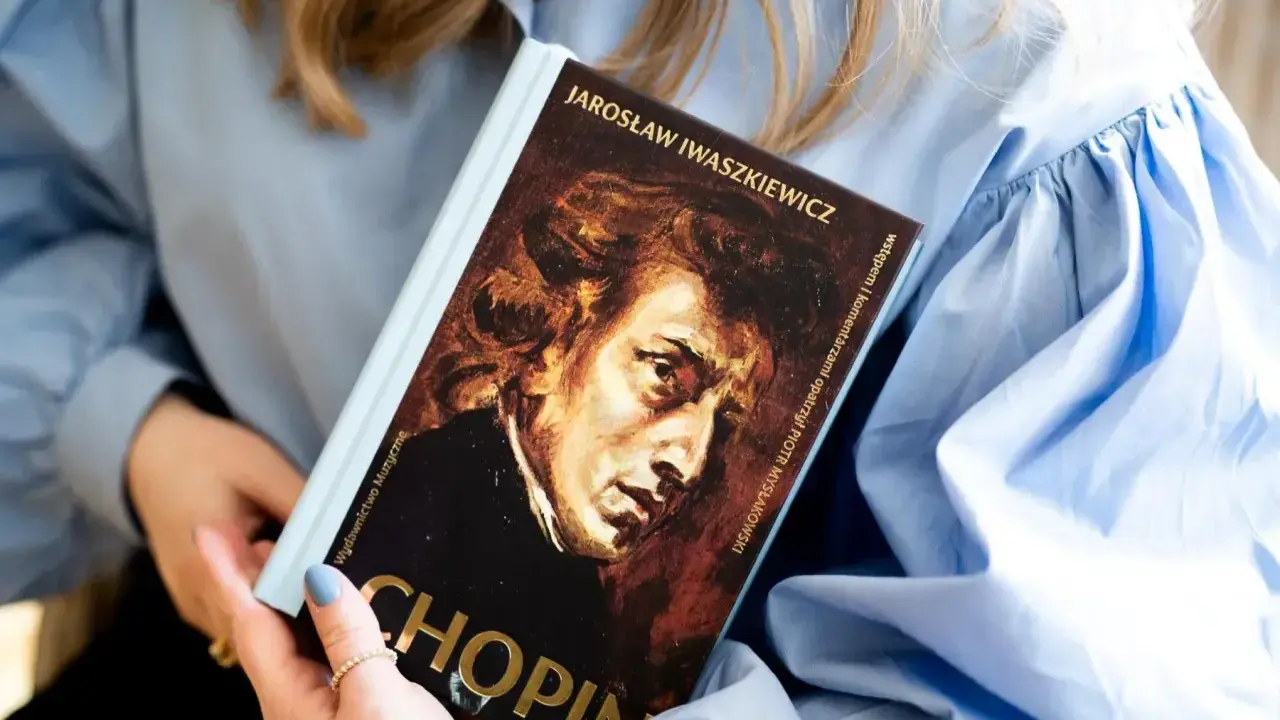 Kobieta trzyma książkę o Chopinie. Portret kompozytora na okładce. Piękna muzyka Chopina.