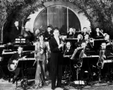 Orkiestra grająca muzykę lat 30. na scenie. Wokalistka w eleganckiej sukni, klarnetysta, gitarzysta i sekcja dęta.