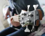 Osoba gra na gitarze basowej, tworząc głębokie akordy basowe.