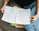 Osoba przegląda nuty, na których widnieje cząstka utworu muzycznego.