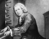 Johann Sebastian Bach, mistrz klawiatury, grający na organach. Jego dłonie spoczywają na klawiszach, a wzrok skierowany jest w stronę widza.