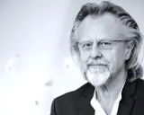 Portret mężczyzny z siwą brodą i długimi włosami, w okularach. Jeden z najlepsi współcześni kompozytorzy.