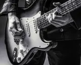 Ręce muzyka grające na gitarze do metalu. Czarno-białe ujęcie z bliska.