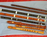 Różnorodne instrumenty renesansu, w tym flety proste o różnych rozmiarach i materiałach, ułożone na niebieskim tle.