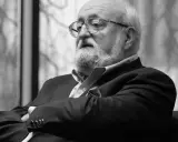 Krzysztof Penderecki w okularach, z brodą, w garniturze. Jego utwory to arcydzieła muzyki współczesnej.