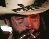Amerykańskie gwiazdy muzyki country, jak Post Malone, w kowbojskim kapeluszu, z tatuażami na twarzy, palący papierosa.