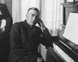Karol Szymanowski, zamyślony przy fortepianie, z nutami na pulpicie.