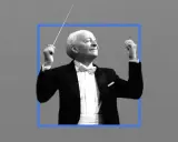 Witold Lutosławski, kompozytor, dyryguje orkiestrą w eleganckim fraku.