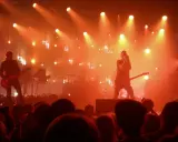 Koncertowa scena w pomarańczowych światłach. Wokalista śpiewa, gitarzysta gra. To musi być ich żółta piosenka!
