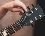 Dłoń kręci kluczem, by nastroić gitarę klasyczną. Idealne brzmienie czeka!
