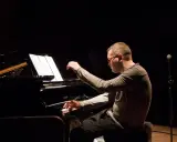 Znany polski kompozytor i pianista jazzowy, w skupieniu gra na fortepianie podczas koncertu.