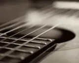 Zbliżenie na struny gitary, jakby grały melodię w stylu Claude'a Debussy'ego.