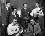 Zespół młodych muzyków, być może najsłynniejsi przedstawiciele jazzu, pozuje z instrumentami: kontrabasem, saksofonem, gitarą i perkusją.
