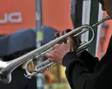 Muzyk gra na trąbce, tworząc dźwięki blues muzyka. W tle deszcz i parasol.