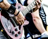 Muzyk gra na gitarze, przygotowując się do wykonania coverów piosenek.