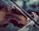 Dłoń gra na skrzypcach Stradivarius, wydobywając z nich magiczne dźwięki.