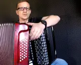 Mężczyzna w okularach uczy się grać na akordeonie. Lekcje gry na akordeonie dla dorosłych to świetny pomysł na rozwijanie pasji.