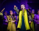 Aktorzy w barwnych strojach na scenie, przypominający postacie z operetki Moniuszki.