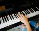 Dłoń grająca piosenkę na fortepianie Steinway.