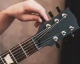 Dłoń kręci kluczem, strojąc gitarę. Słychać czysty dźwięk e, gotowy do gry.