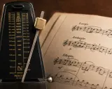 Metronom obok nut, gdzie widnieje tempo allegretto.