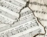 Stare, nadpalone nuty muzyczne z zapisanymi akordami i tekstem.