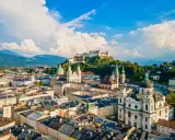 Widok na miasto z górami w tle, w tym Hohensalzburg. To ojczyzna Mozarta, Salzburga, z pięknymi kościołami i zabytkową architekturą.