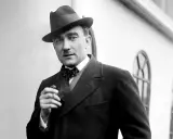 Elegancki mężczyzna w kapeluszu i muszce, palący papierosa. Może to Karol Szymanowski, który marzy o swoich dzieciach.