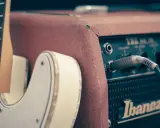 Biała gitara elektryczna podłączona do wzmacniacza Ibanez. Idealny zestaw, by zacząć naukę, jak grać na gitarze elektrycznej.