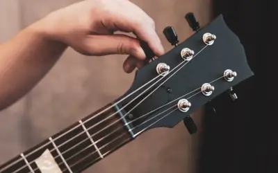 Dłoń kręci kluczem, by nastroić gitarę klasyczną. Idealne brzmienie czeka!