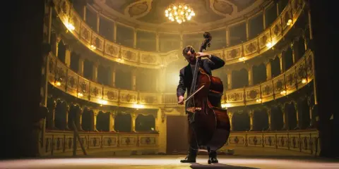Kontrabasista na scenie teatru, niczym jeden z klasyków przedstawicieli muzyki epoki klasycyzmu, gra w blasku złotych lóż.