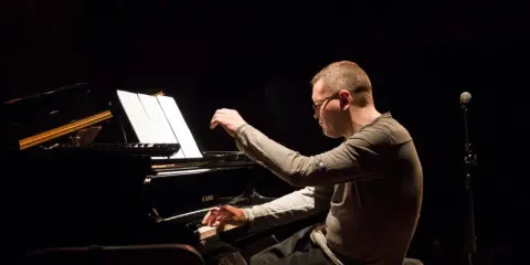 Znany polski kompozytor i pianista jazzowy, w skupieniu gra na fortepianie podczas koncertu.